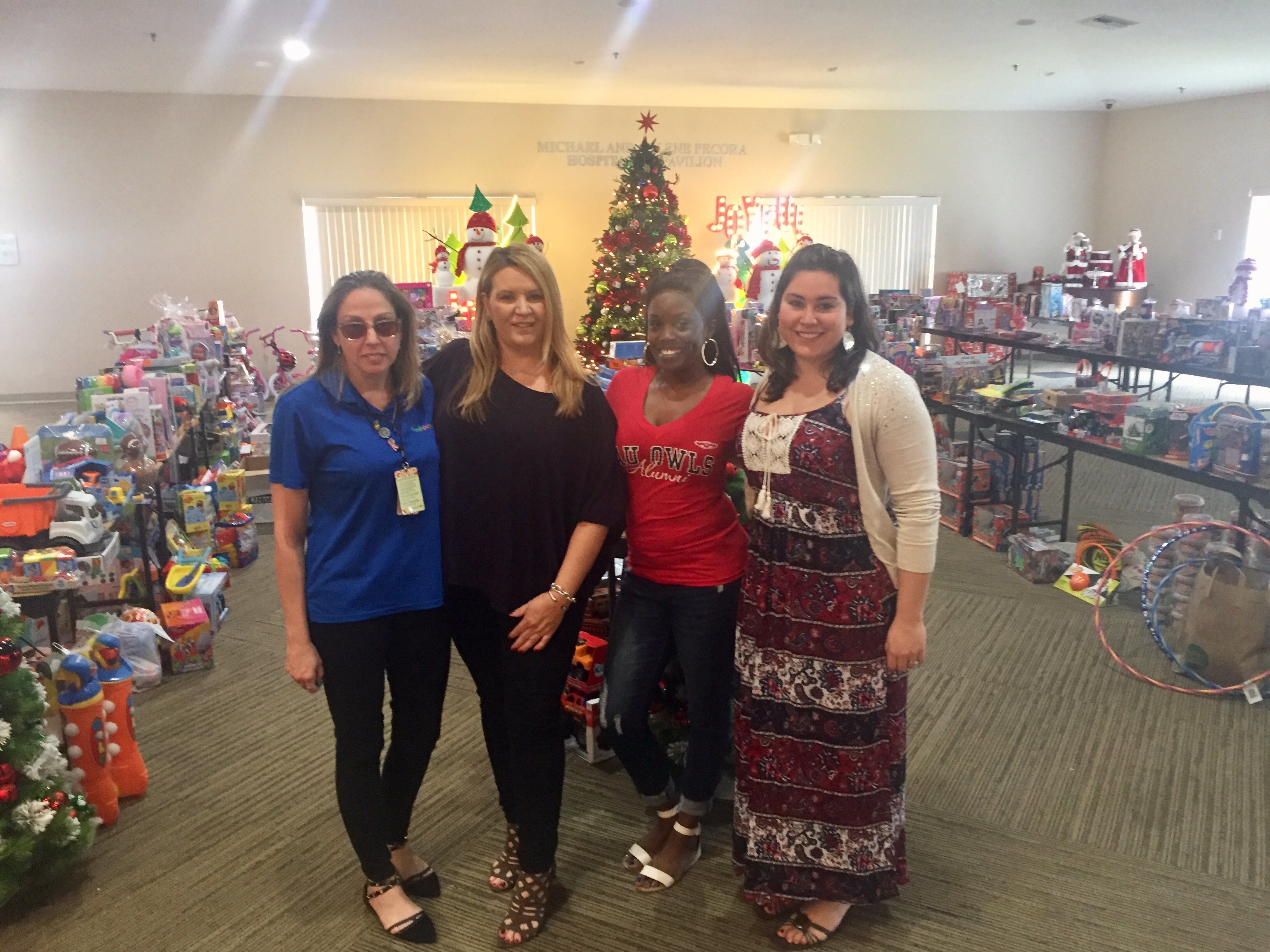 Jennifer Walls, Kelly Walsh, Janae Watson & Cindy Brunetto in front of the many holiday donations from the community to benefit Women In Distress. They are displayed so the families may go "shopping.”